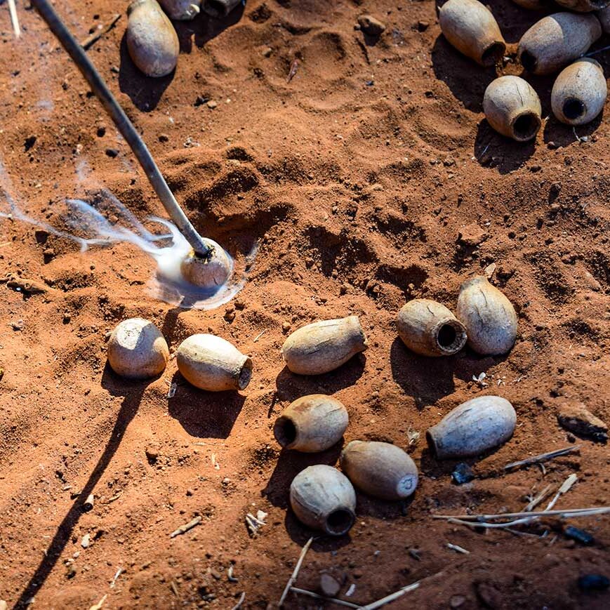 Burning holes in the tartu (gum nut) so they can be painted and made into necklaces